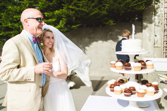 bride looking at wedding cake with her dad