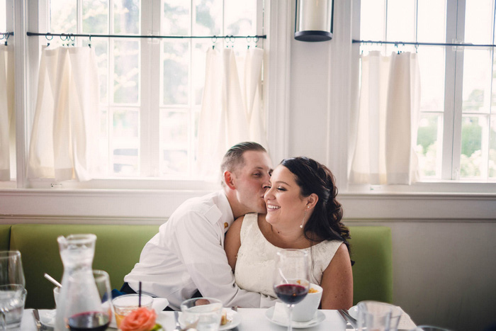 groom kissing bride on the cheek at dinner