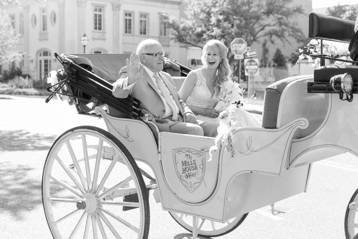 bride laughing in horse drawn carriage with her dad