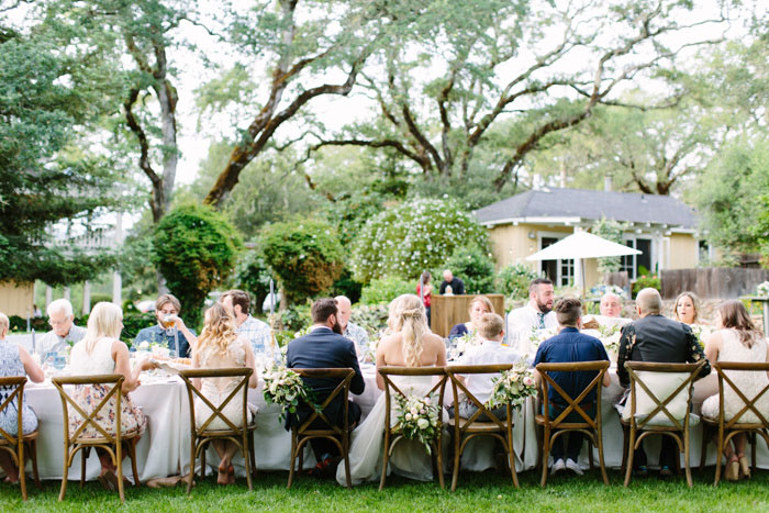 wedding guests seated out large outdoor table