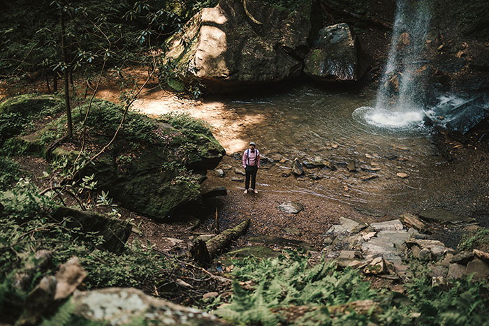 groom waiting at base of waterfall