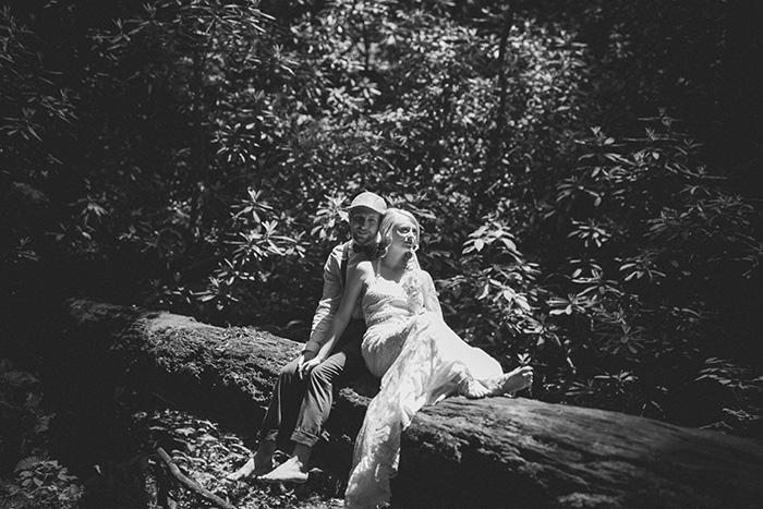 bride and groom sitting on log