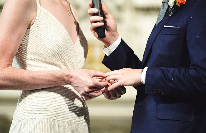 bride putting ring on groom's finger