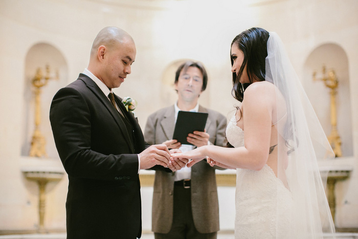 groom putting ring on bride's finger