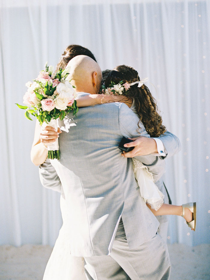 groom hugging bride and daughter