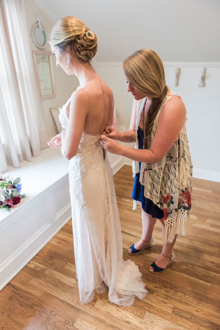 bride being zipped into her dress